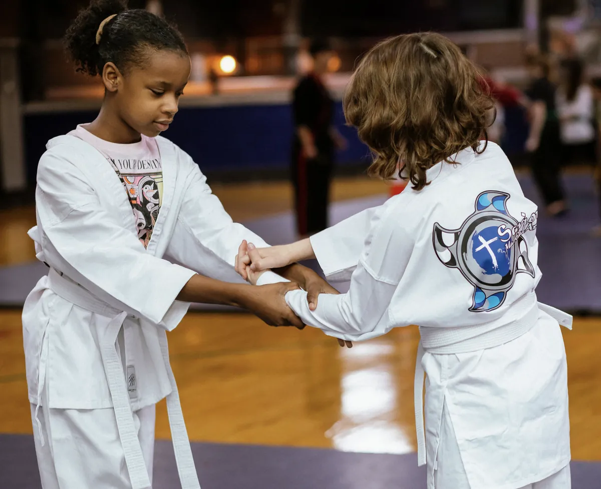 Two young students in white gis working a partner drill in class